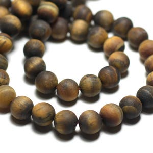 Può includere: Una collana di perle di occhio di tigre marrone. Le perle sono rotonde e hanno una finitura liscia e lucida. Le perle sono infilate su un filo elastico trasparente.
