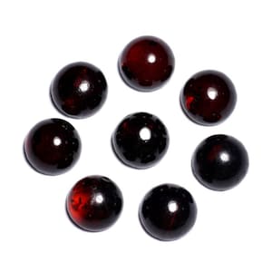 Peut inclure: Huit billes de verre rouge foncé, disposées en cercle sur un fond blanc.