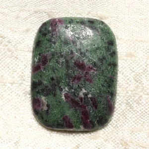Puede incluir: Un cabujón de piedra preciosa verde y roja con un acabado rugoso y natural. La piedra tiene un aspecto moteado con inclusiones verde oscuro, verde claro y rojo.