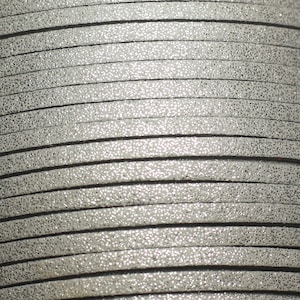 Peut inclure: Gros plan d'un rouleau de cordon en cuir argenté pailleté. Le cordon est fait d'un cuir souple et doux avec une finition pailletée fine. Le cordon est parfait pour la fabrication de bijoux, d'accessoires et d'autres projets.