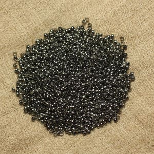 May include: A large pile of small, black metal beads. The beads are round and have a smooth, shiny finish.