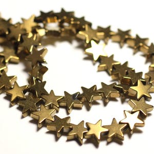 Puede incluir: Una hebra de cuentas doradas en forma de estrella. Las cuentas son de metal y tienen un acabado brillante.