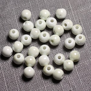 Peut inclure: Un ensemble de perles rondes en céramique blanc cassé. Les perles sont lisses et brillantes.