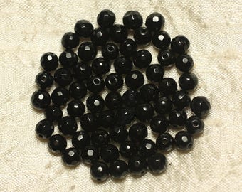 May include: A pile of black faceted glass beads. The beads are round and have a shiny finish.