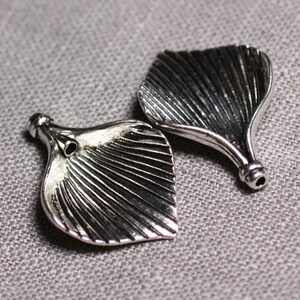May include: Two silver metal leaf-shaped charms with a textured surface and a hole at the top.