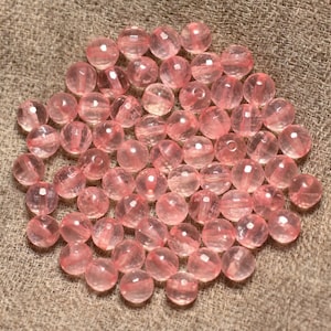 Könnte beinhalten: Ein Haufen rosa Glasperlen, einige sind klar und einige sind undurchsichtig, auf einem braunen Stoffhintergrund.