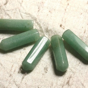 Peut inclure: Cinq baguettes de cristal d'aventurine verte. Chaque baguette est de couleur vert clair avec une surface polie et lisse. Les baguettes ont une forme hexagonale et mesurent environ 5 cm de long.