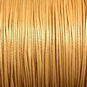 Puede incluir: Primer plano de un carrete de cordón de algodón encerado de color marrón claro.