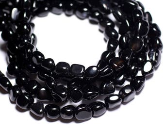 May include: A strand of black gemstone beads, each bead is a smooth, irregular oval shape. The beads are strung together to form a necklace or bracelet.
