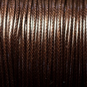 May include: Close-up of a spool of brown waxed cord. The cord is tightly wound and has a subtle sheen.