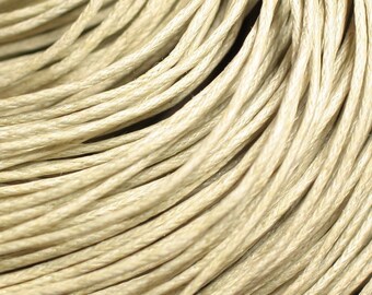 May include: Close-up of a bundle of natural beige colored twine. The twine is tightly wound and has a smooth, slightly textured surface.