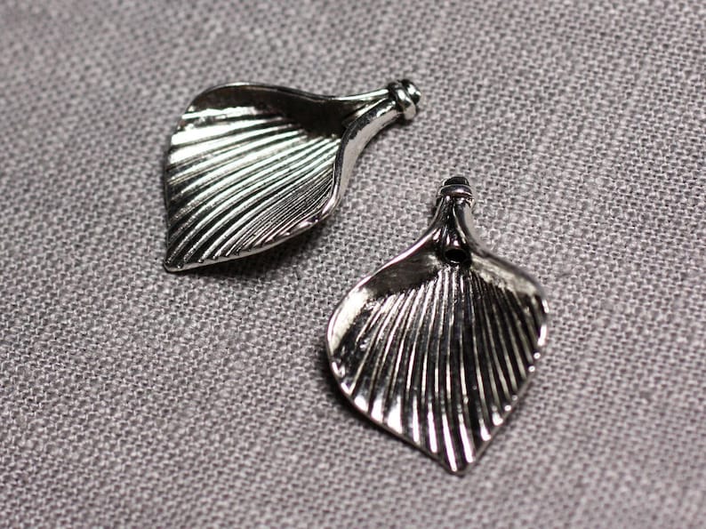 May include: Two silver metal leaf-shaped charms with a textured design.
