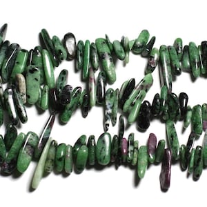 Pode incluir: Um fio de contas de pedras preciosas verdes, pretas e rosadas. As contas são longas e estreitas, com um acabamento áspero e natural.