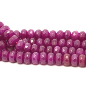 May include: A strand of faceted pink jade beads. The beads are round and have a smooth, polished finish.