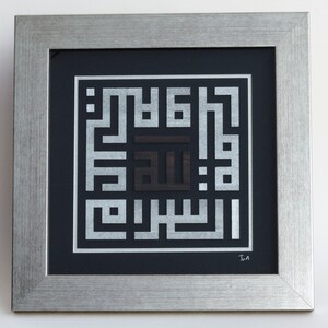 May include: A framed artwork featuring a silver and black Islamic calligraphy design. The design is a square with the word "Allah" in the center. The artwork is framed in a silver frame with a black mat.