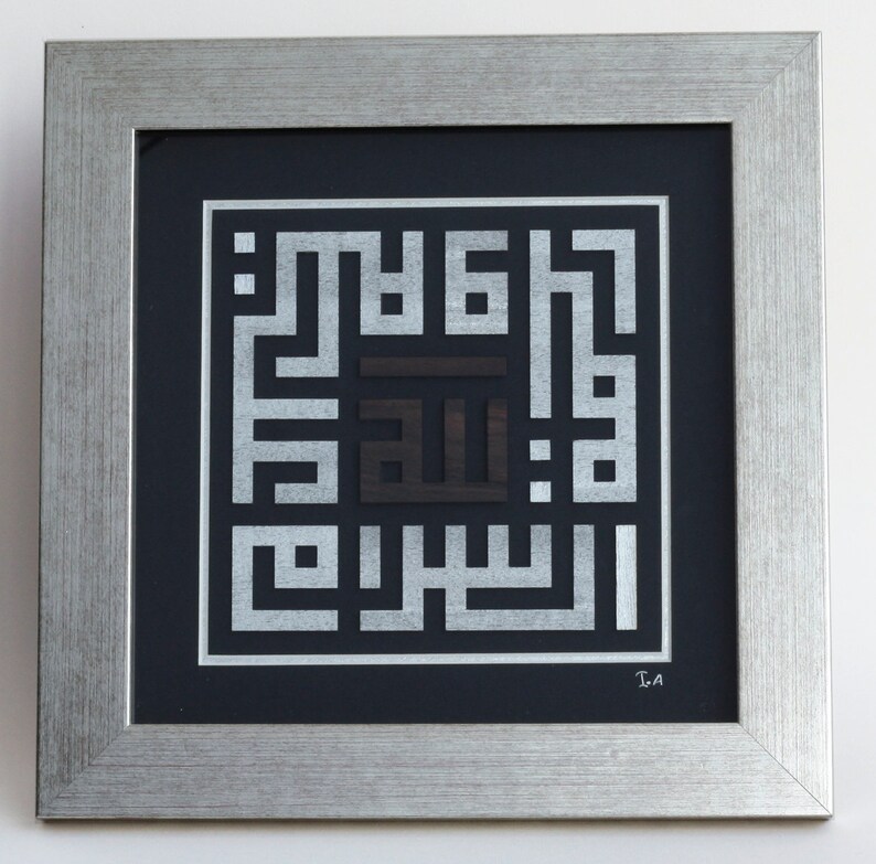 May include: A framed artwork featuring a silver and black Islamic calligraphy design. The design is a square with the word "Allah" in the center. The artwork is framed in a silver frame with a black mat.