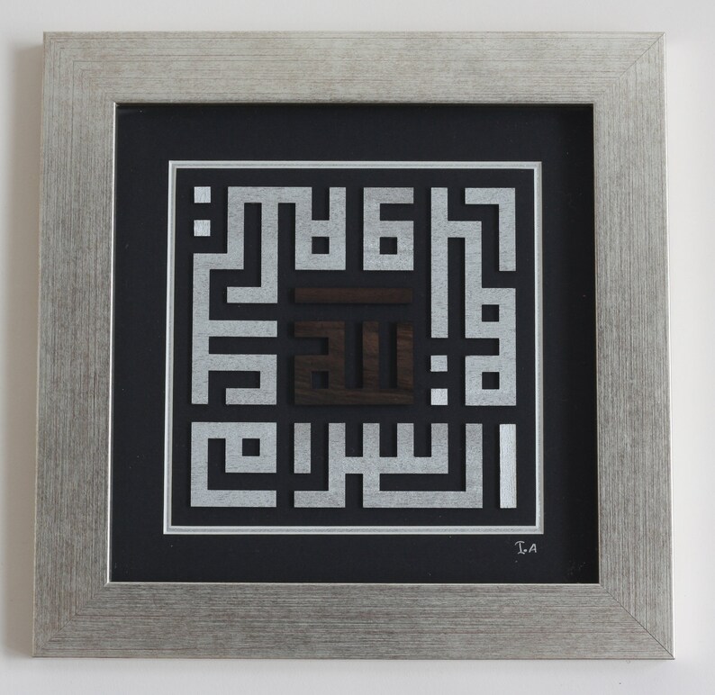May include: A framed artwork featuring a silver and black Islamic calligraphy design. The design is made up of intricate geometric patterns and the word "Allah" is prominently displayed in the center.