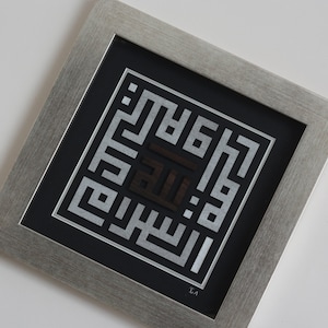 May include: A framed silver and black Islamic calligraphy art piece with the word "Allah" in the center. The artwork is framed in a silver frame with a black mat.