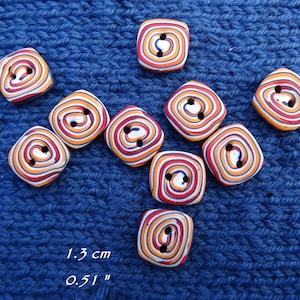 May include: A collection of nine square buttons featuring a swirling pattern of red, orange, white, and black stripes. Each button has two central holes and measures 0.51 inches, as indicated by the text printed on the image.