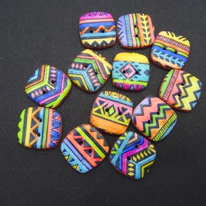 Puede incluir: Una colección de once botones cuadrados con vibrantes patrones geométricos multicolores. Cada botón tiene dos orificios centrales y muestra una variedad de tonos brillantes que incluyen rosa, azul, amarillo, naranja y verde con detalles en negro.
