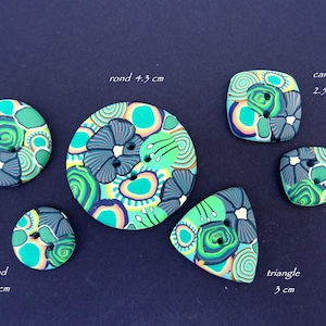 May include: A collection of handmade buttons in various shapes: round, square, and triangular. The buttons feature a colorful, abstract design with shades of teal, green, and blue. Sizes range from 2 cm to 4.3 cm.