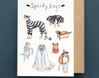 Può includere: Biglietto di auguri di Halloween con illustrazioni di cani in costume. Il biglietto è intitolato "Spooky Dogs" e raffigura cani vestiti da prigioniero, ragno, hot dog, fantasma e strega, ad acquerello.