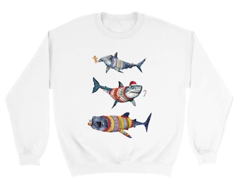 Pode incluir: Camisola branca com três tubarões de desenho animado decorados para as festas. Os tubarões usam camisolas, chapéus e seguram guloseimas. O tubarão superior segura um homem de gengibre. Disposição vertical.