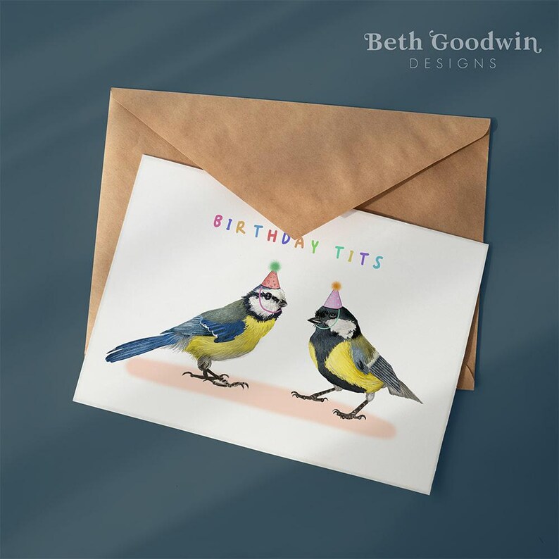 May include: A birthday card with two bluebirds wearing party hats. The card says "Birthday Tits" in rainbow letters.