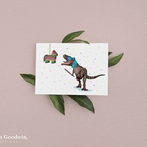 May include: A greeting card featuring a cartoon dinosaur wearing a blindfold and holding a stick, about to hit a colorful pinata. The background is white with confetti.