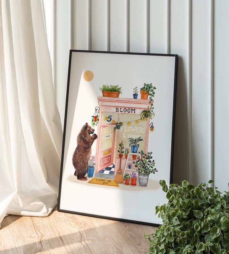 Op de afbeelding: Een aquarelillustratie van een roze winkelgevel met de woorden "Bloom Flowers & Coffee" boven de deur. Een bruine beer staat bij de deur, die een bord heeft met de tekst "Open". Er is een welkommat met de tekst "Come On In".