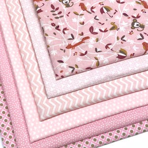 Puede incluir: Una pila de muestras de tela rosa con varios patrones. La tela superior presenta un diseño caprichoso con monos, pájaros y zorros entre ramas y hojas. Otras telas incluyen patrones de chevron, lunares y florales en tonos de rosa y blanco.