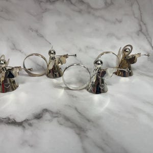 May include: A set of three ceramic mugs with a speckled, matte finish. The mugs are in shades of cream, light gray, and dark gray. Each mug has a simple, minimalist design, perfect for coffee or tea.