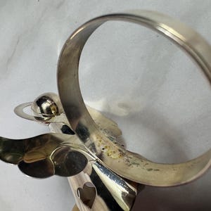 May include: A white ceramic mug with a black handle and the text "But First, Coffee" in a bold, black font. The mug is set against a blurred background, suggesting a cozy setting.