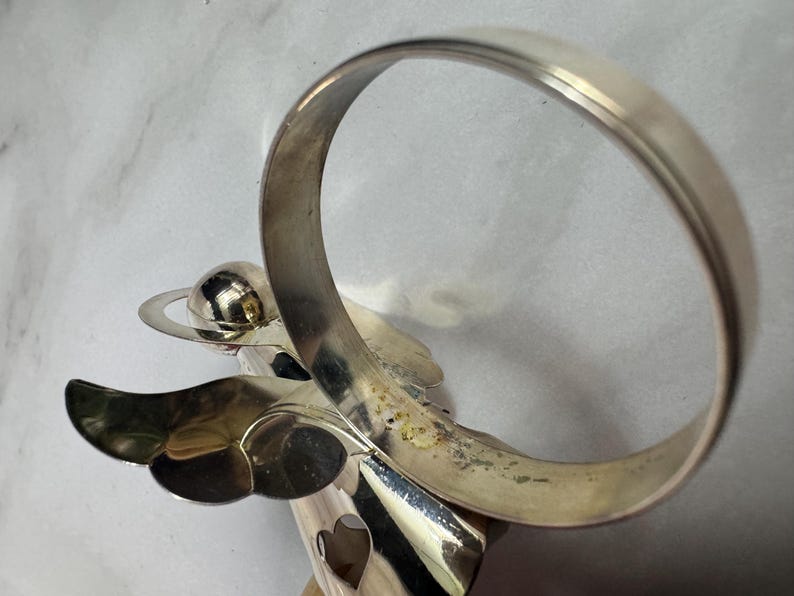 May include: A white ceramic mug with a black handle and the text "But First, Coffee" in a bold, black font. The mug is set against a blurred background, suggesting a cozy setting.