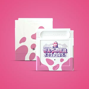May include: A white Game Boy cartridge with pink cow spots and Japanese text. The cartridge features the game title "Zelda's Dream Island" and a graphic of an egg. The background is a solid pink.