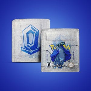 Op de afbeelding: Twee heldere, glinsterende spelcartridges. Eén heeft een blauw en wit geometrisch ontwerp. De andere toont een blauw Pokémon-personage met de tekst "Pokemon Crystal Clear Version" en het Nintendo-logo.
