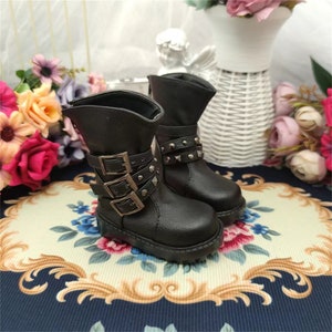May include: A pair of black leather doll boots with silver buckles and studs. The boots have a chunky heel and a rounded toe.
