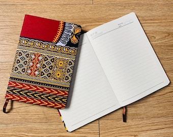 May include: A red, black, and yellow patterned notebook with a blank lined notebook attached. The patterned notebook has a geometric design.