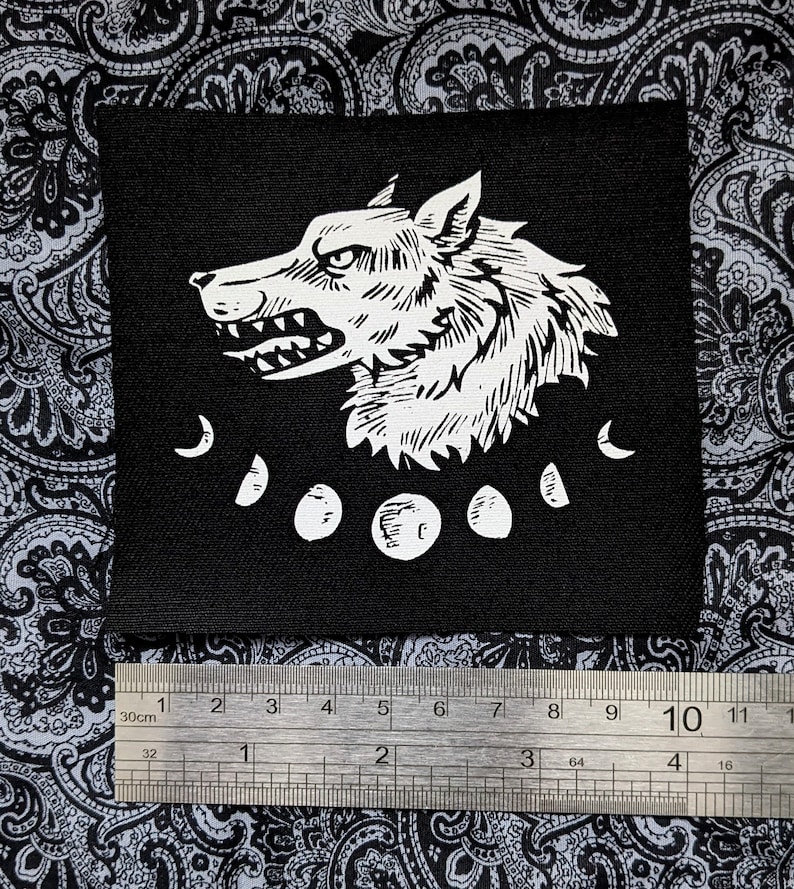 May include: Black and white iron-on patch featuring a wolf's head with a snarling expression and five crescent moons.