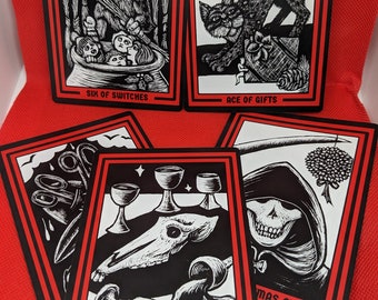 May include: A set of tarot cards with black and white illustrations. The cards feature images of a goat-like creature, a cat, a skull, and a figure in a hooded robe. The cards are labeled with the names "Six of Switches", "Ace of Gifts", "Five of Wassail Cups", and "Mas Future".