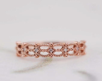 May include: A delicate rose gold band ring with a delicate filigree design and small clear gemstones.