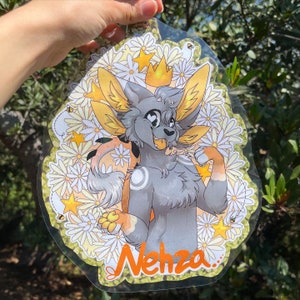 May include: A gray and white furry creature with a yellow crown and a yellow and white flower background. The creature is smiling and has a white circle on its chest. The text "Nehza" is written in orange at the bottom of the image.