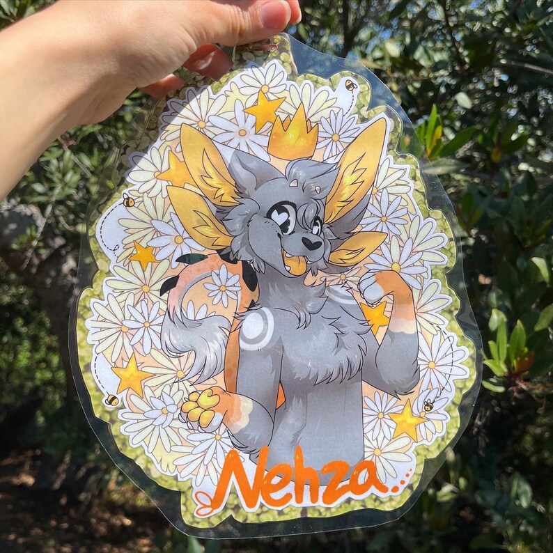 May include: A gray and white furry creature with a yellow crown and a yellow and white flower background. The creature is smiling and has a white circle on its chest. The text "Nehza" is written in orange at the bottom of the image.