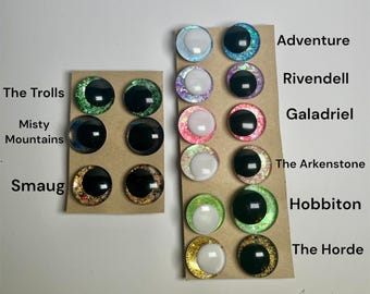 May include: A set of 10 pairs of colorful, glittery, and iridescent resin eyes with black pupils. Each pair is labeled with a different name, such as "The Trolls", "Misty Mountains", "Smaug", "Adventure", "Rivendell", "Galadriel", "The Arkenstone", "Hobbiton", and "The Horde".