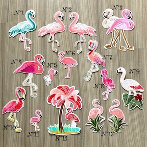 Peut inclure: Un ensemble de 13 patchs thermocollants en forme de flamants roses, dont un palmier rose avec un flamant rose. Les patchs sont numérotés de 1 à 13.