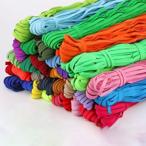 Peut inclure: Un tas de bandes élastiques colorées, comprenant du vert, du bleu, de l'orange, du rose et du violet. Les bandes sont soigneusement regroupées et empilées, présentant une gamme de couleurs vives. Idéal pour divers projets de couture et d'artisanat.