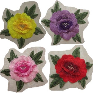 Peut inclure: Quatre patchs de fleurs brodés dans différentes couleurs : jaune, violet, rose et rouge. Chaque patch présente une fleur avec des feuilles vertes.