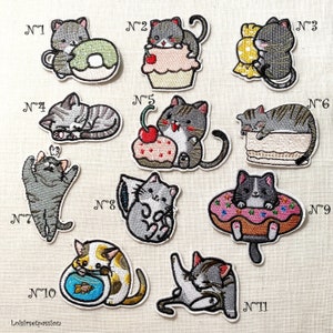 May include: Ten embroidered iron-on patches featuring cute cats in various poses and settings. The patches are numbered 1 through 10 and feature designs such as a cat sleeping on a cake, a cat holding a donut, and a cat playing with a fish.