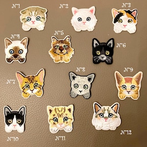 Op de afbeelding: Een verzameling van twaalf geborduurde kattenpatches, elk met unieke gezichtskenmerken en kleuren. De patches tonen verschillende rassen, met details zoals oogkleur en vachtpatronen. Elke patch is genummerd van 1 tot 12.