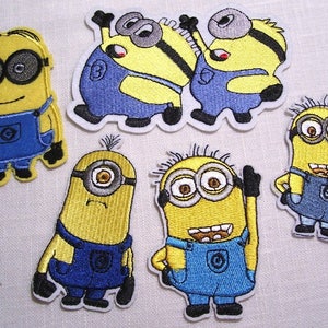 May include: Embroidered patches featuring yellow Minion characters in blue overalls. The patches depict various poses and expressions, including waving and smiling. The patches are outlined in white.